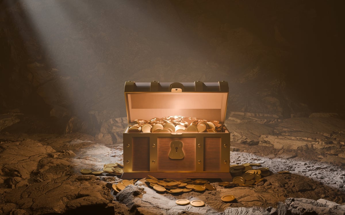 Treasure chest overflowing with gold coins dramatically lit by spotlight in mysterious cave — the thrill of discovery and finding treasure