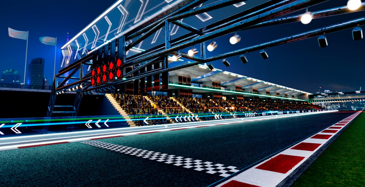 Racetrack starting grid with lights and grandstands at night anticipating a speed event